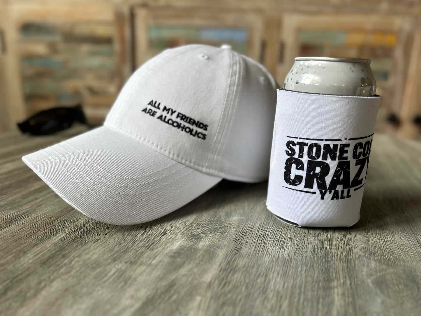 White cap and can cooler with text on a wooden surface