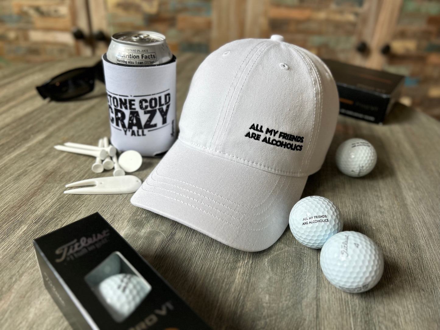 White cap with text, golf balls, and a can on a wooden surface
